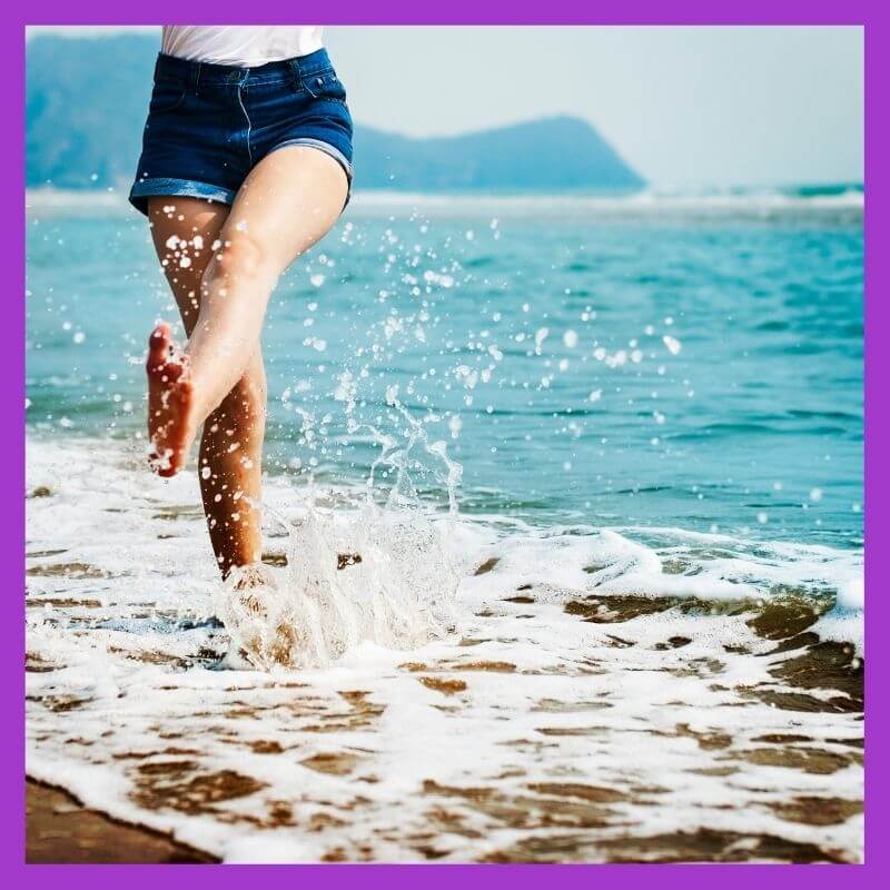 Happy girl kicking water on the beach